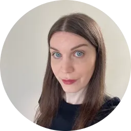 A photo of me, a 41-year-old white woman with blue eyes and long brown hair parted in the centre, wearing a black crewneck top